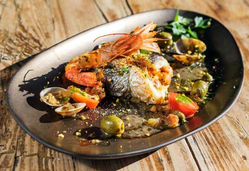 Dorada rellena de mató y verduras con gambas, almejas,olivas y alcaparras